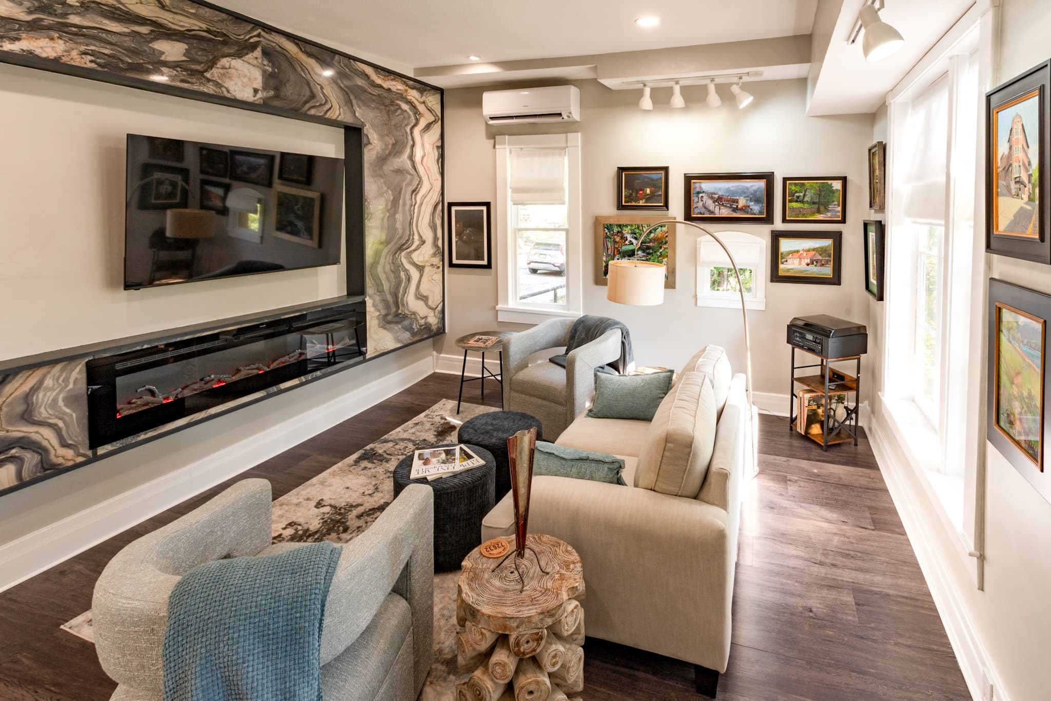 Modern living room with a stone feature wall, fireplace, and various artwork displayed.