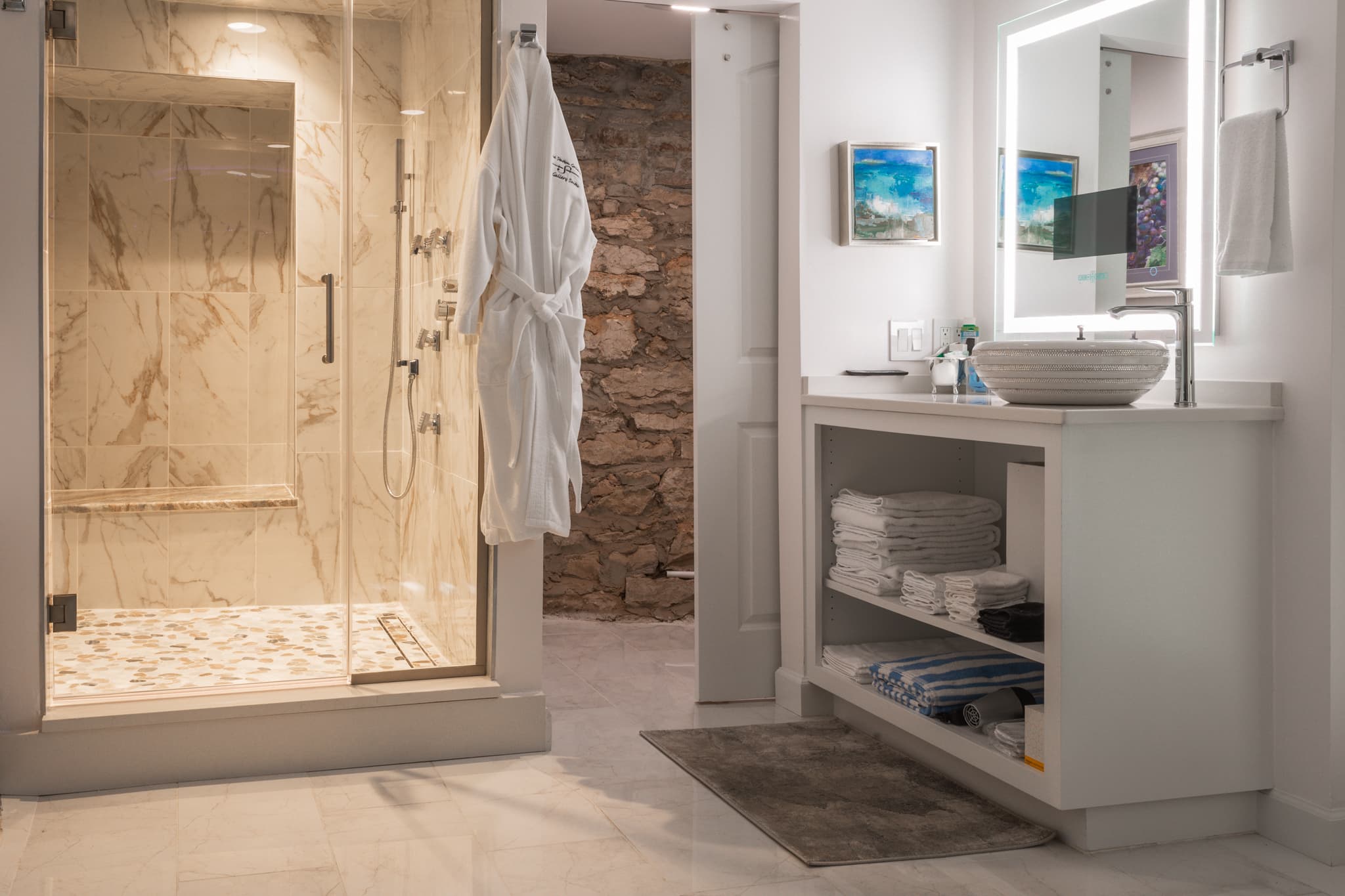 A modern bathroom featuring a glass shower, neatly arranged towels, and a large mirror.
